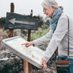 Uśmiechnięta starsza kobieta odwiedzająca wyspę Tenerife czyta informacje turystyczne o okolicy Chirche