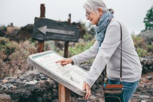 Uśmiechnięta starsza kobieta odwiedzająca wyspę Tenerife czyta informacje turystyczne o okolicy Chirche