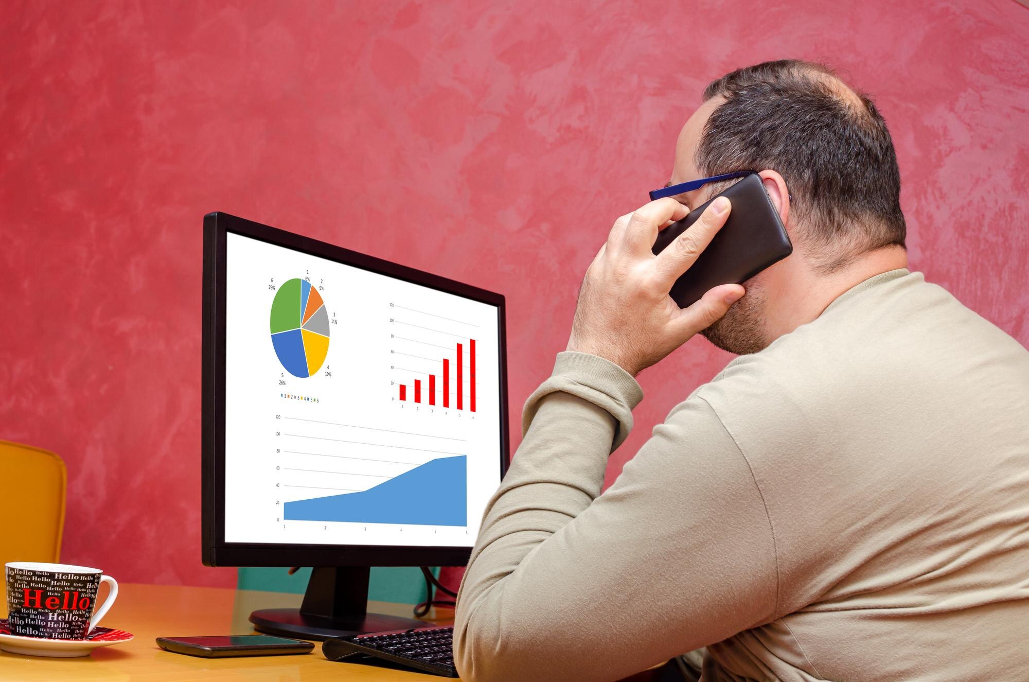 Biznesmen za pomocą komputera używającego telefonu komórkowego podczas pracy jako freelancer
