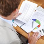 Przedsiębiorca dokumenty i kalkulator do rachunkowości finansowej i sprawozdania budżetowego lub analizy przychodów i zysków Profesjonalny księgowy z statystykami planowania arkusza kalkulacyjnego i liczbami sprzedaży