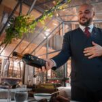 Pewny siebie kelner prezentujący wino w luksusowej restauracji