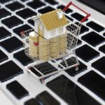 Koncepcja biznesowa online z makietą domu i stosem monet w koszyku