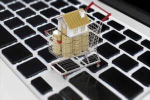 Koncepcja biznesowa online z makietą domu i stosem monet w koszyku