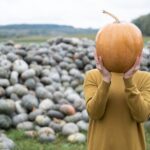 Piękna młoda kobieta w musztardowej sukience z dyni pomarańczowy odkryty na patchu.