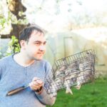 Mężczyzna trzymający grillowaną rybę w stalowej siatce