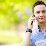 Mężczyzna trzymający mapę na zewnątrz i rozmawiający przez telefon