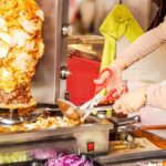 Arabka sprzedająca jedzenie uliczne umiejętnie zakręca kebab gyro