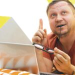 Mężczyzna na łóżku pracujący na laptopie. ludzkie emocje