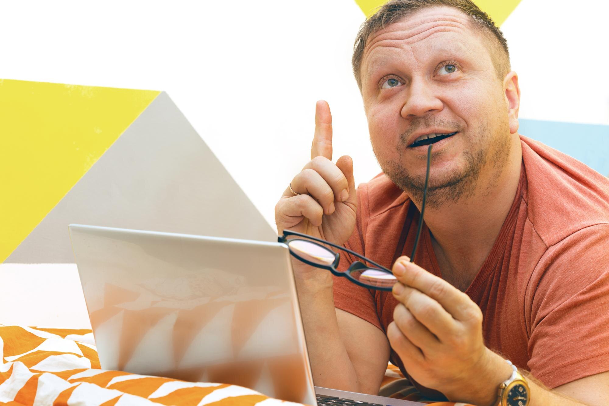 Mężczyzna na łóżku pracujący na laptopie. ludzkie emocje
