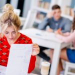 Młody żeński studiowanie z notatnikiem przy biblioteką