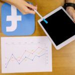 Zasięrzutny widok osoba trzyma cyfrową pastylkę analizuje facebook wykres