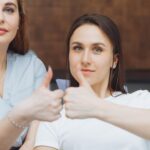 Dziewczyna jest zadowolona z wizyty u dentysty Koncepcja bezbolesnego leczenia stomatologicznego Piękny szeroki uśmiech dziecka Kciuki w górę