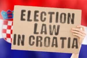 Fraza Prawo wyborcze w Chorwacji na banerze w rękach mężczyzn z zamazaną chorwacką flagą w tle Konstytucja Polityczny Senat Zagrzeb Elektorat Większość