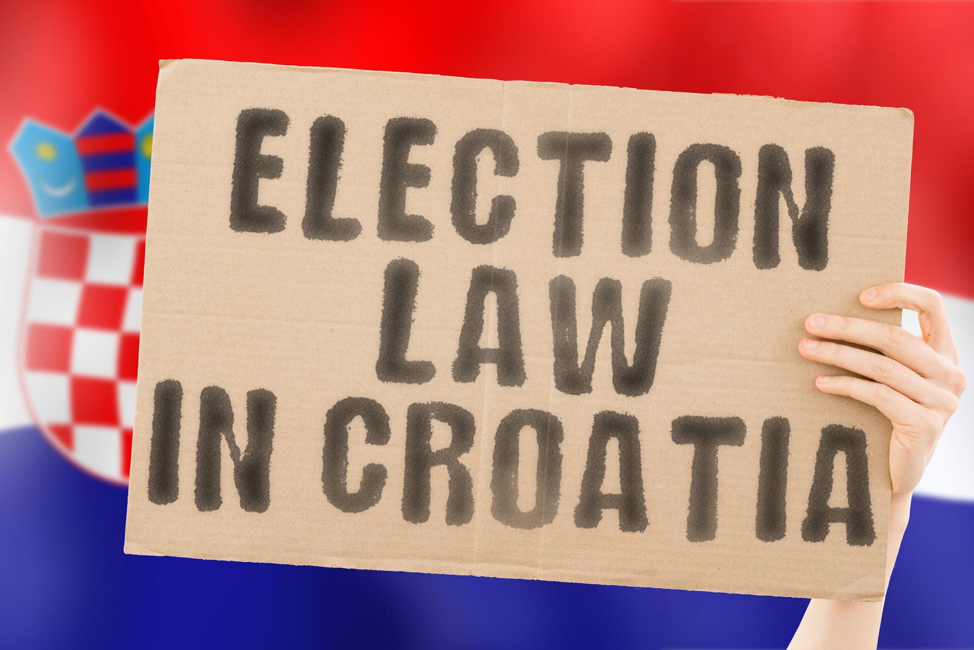 Fraza Prawo wyborcze w Chorwacji na banerze w rękach mężczyzn z zamazaną chorwacką flagą w tle Konstytucja Polityczny Senat Zagrzeb Elektorat Większość