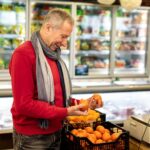 Mężczyzna kupujący w supermarkecie wybierający mandarynki