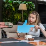 Podekscytowana pani trzymająca niebieską tablicę pomysłów i patrząca w kamerę w restauracji