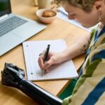 Młoda bizneswoman z częściowym ramieniem robi notatki lub spisuje plan