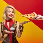 Ręka dająca kawałek pizzy z serem i sięgająca do ręki na czerwonym i żółtym tle