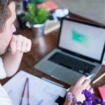 Kaukaski mężczyzna pracuje na laptopie siedząc w swoim nowoczesnym biurze Koncepcja młodych ludzi korzystających z miejsca coworkingowego