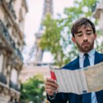 Wakacje w Paryżu Mężczyzna w garniturze korzystający z mapy na Paris France Street z widokiem na Wieżę Eiffla