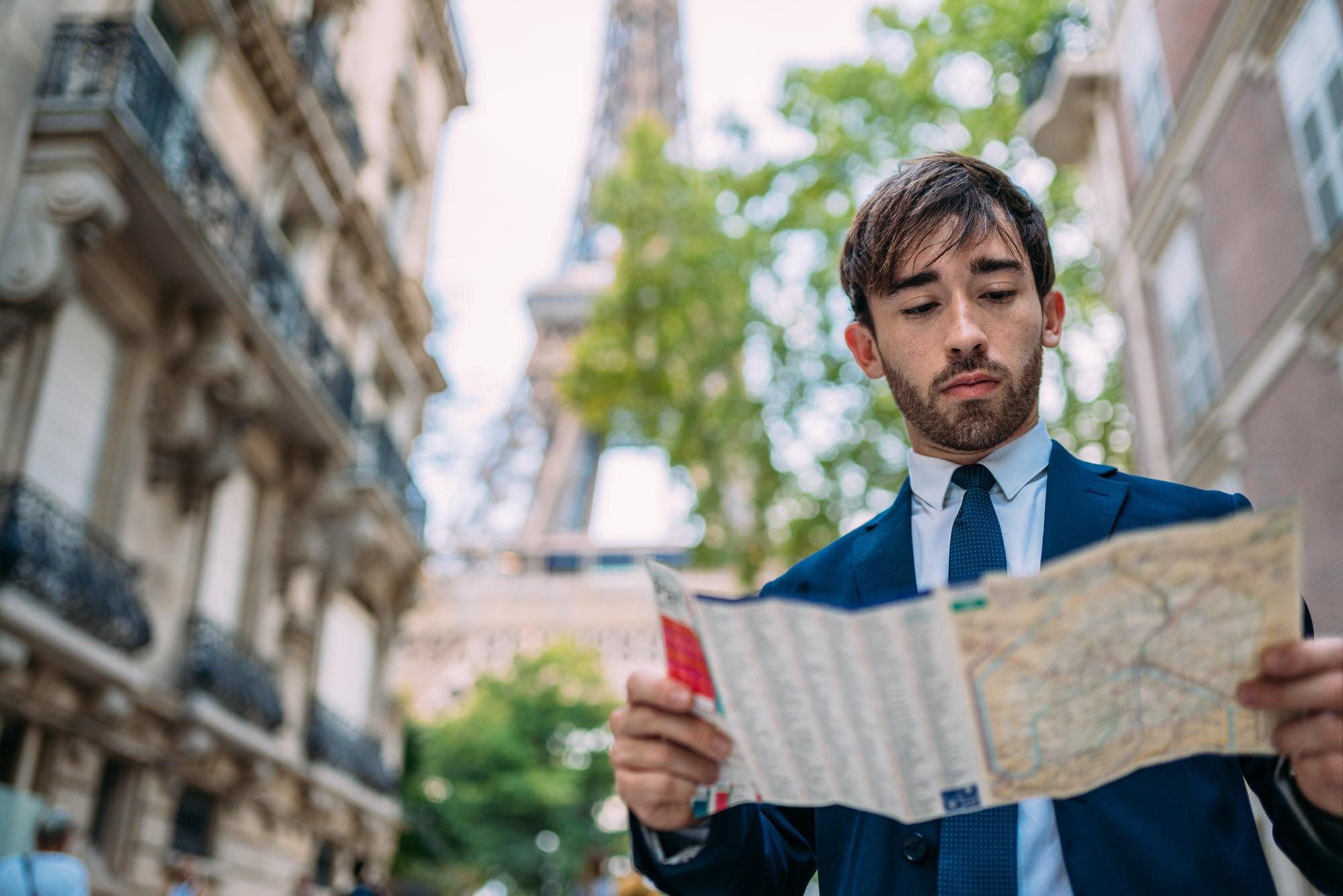 Wakacje w Paryżu Mężczyzna w garniturze korzystający z mapy na Paris France Street z widokiem na Wieżę Eiffla