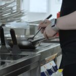 Profesjonalny szef kuchni przygotowuje danie gastronomiczne w patelni przy użyciu składników i naczyń kuchennych Szef kuchni gotuje w kuchni restauracji Praca kucharza w kuchni z bliska