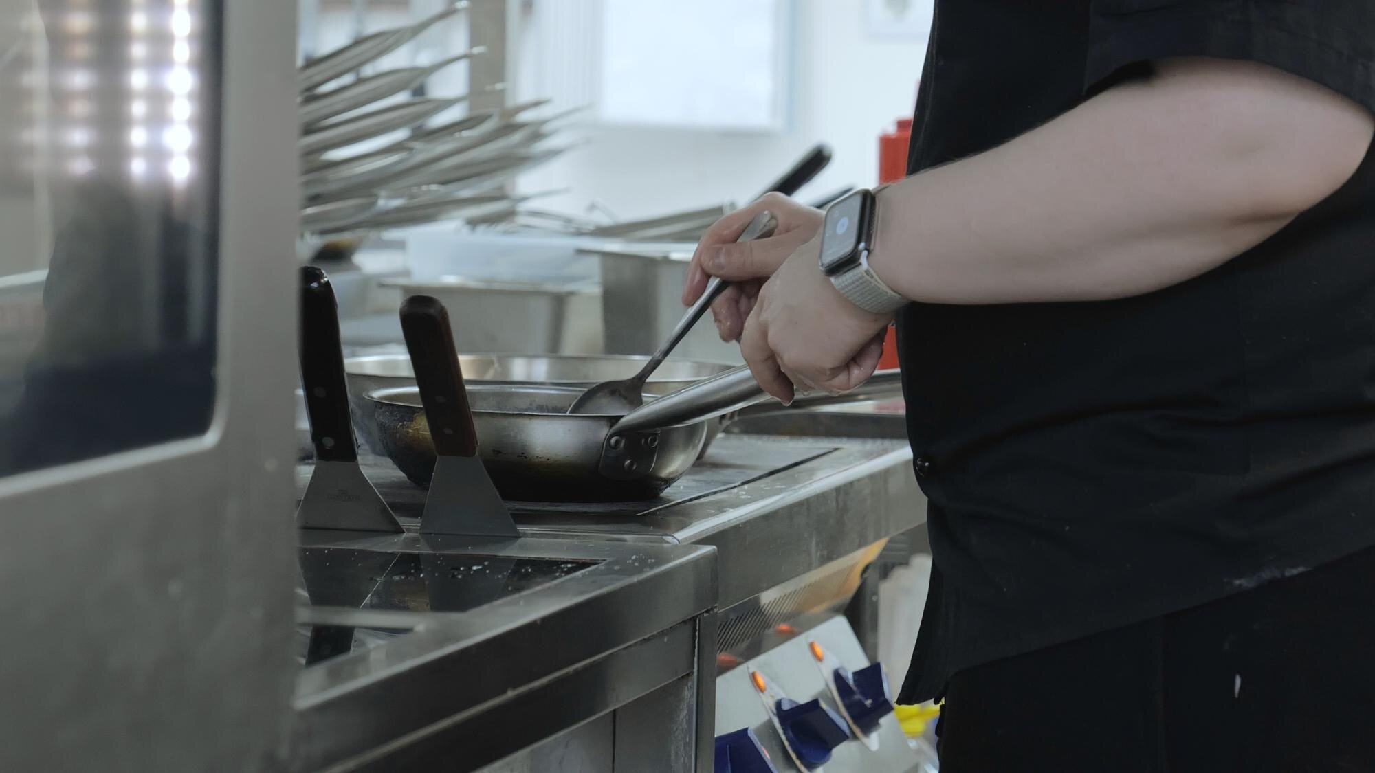 Profesjonalny szef kuchni przygotowuje danie gastronomiczne w patelni przy użyciu składników i naczyń kuchennych Szef kuchni gotuje w kuchni restauracji Praca kucharza w kuchni z bliska