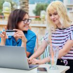 Matka i nastoletnia córka robią razem zakupy online za pomocą laptopa