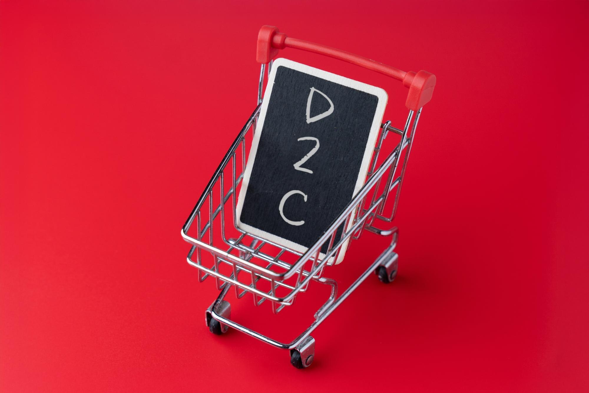 Mini shopping cart holding a chalkboard with D2C text Direct to consumer business model ecommerce