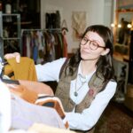 Young biracial woman browsing second hand clothing in vintage store