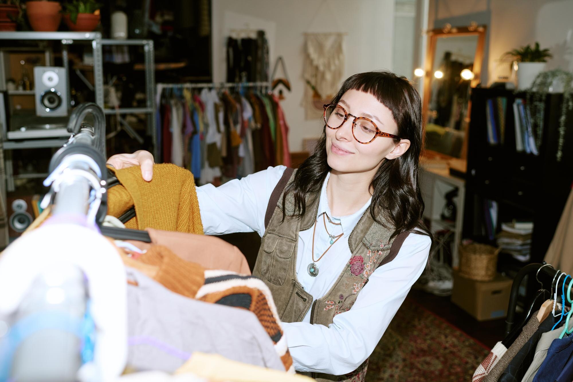 Young biracial woman browsing second hand clothing in vintage store