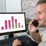 Uśmiechnięty młody biznesmen w biurze rozmawia przez telefon