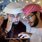 Dwóch arabskich mężczyzn z tabletem w mieście w nocy