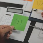 Close up ux developer i ui designer brainstorming o interfejsie aplikacji mobilnej wireframe design na stole z klientem breif i kod kolorowy w nowoczesnym biurzeCreative agencja rozwoju cyfrowego